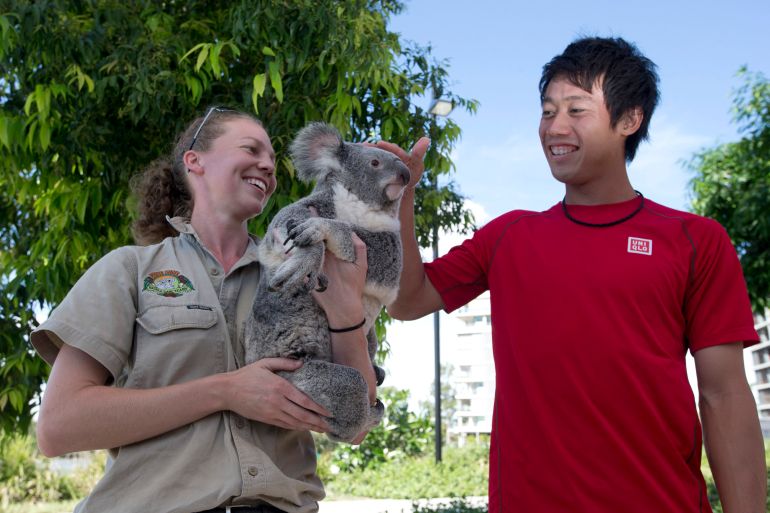 Kei Nishikori of Japan meets Tinkerbell, a native Australian koala from the Lone Pine Koala Sanctuary, and her handler Melanie Harth during the Brisbane International tennis tournament in Brisbane, January 6, 2015. REUTERS/Jason Reed (AUSTRALIA - Tags: SPORT TENNIS ANIMALS)