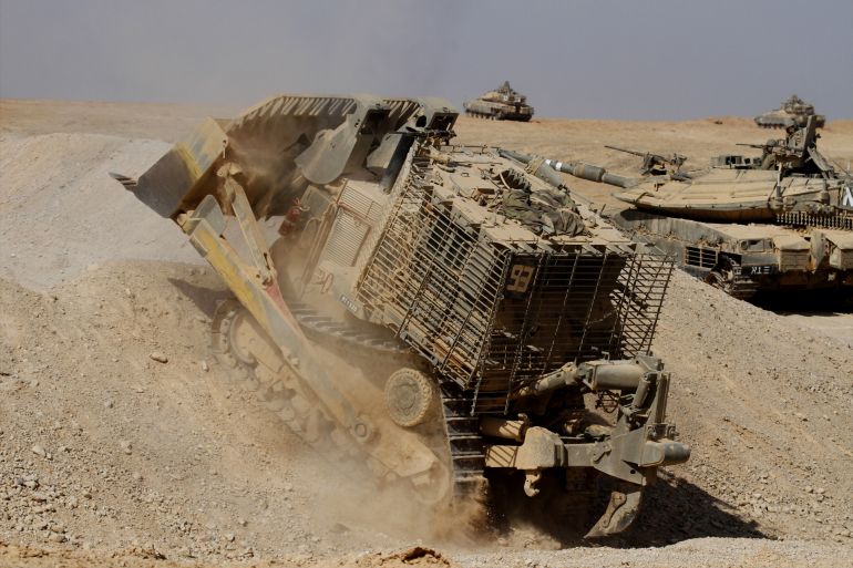 An Israel Defense Force armoured Caterpillar D-9 clearing the way for Mark IV main battle tank during an exercise. - stock photo - غيتي