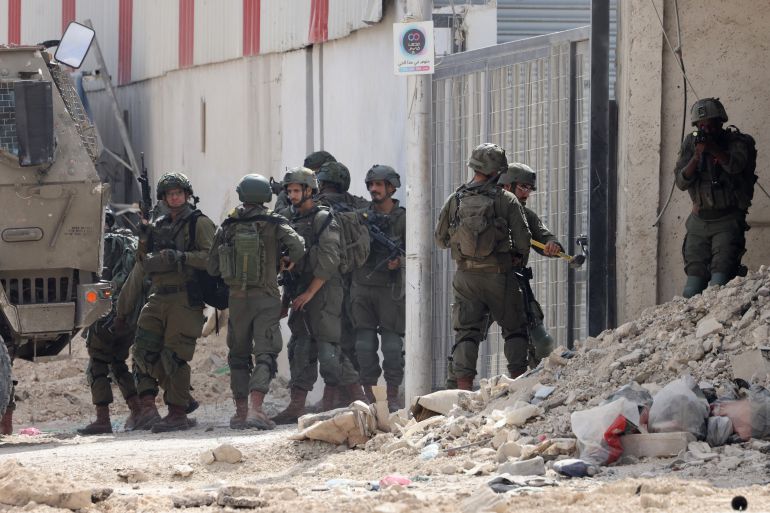 Israeli soldiers operate during a raid in the Nur Shams camp for Palestinian refugees near the city of Tulkarem in the Israeli-occupied West Bank on August 28, 2024. - At least 10 Palestinians were killed in Israeli raids and strikes in several towns in the north of the occupied West Bank, a spokesman for the Red Crescent said on August 28. The operation comes two days after Israel said it carried out an air strike on the West Bank that the Palestinian Authority reported killed five people. (Photo by JAAFAR ASHTIYEH / AFP)