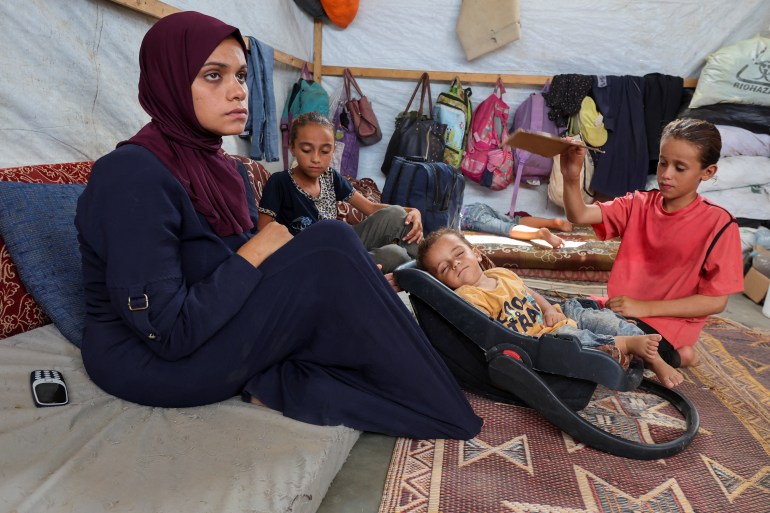 Palestinian boy Abdul Rahman Abu Al-Jidyan, who is the first person to contract polio in Gaza in 25 years, is fanned by his sister as his mother sits in their tent, in Deir Al-Balah, in the central Gaza Strip August 28, 2024. REUTERS/Ramadan Abed