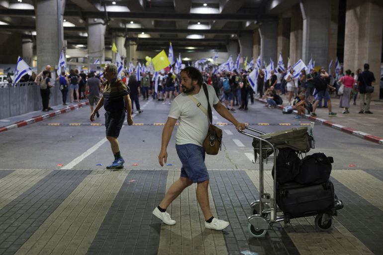 A man pushes a luggage trolley, as anti-government protesters at Ben Gurion International Airport demonstrate against Israeli Prime Minister Benjamin Netanyahu's departure to the U.S., where he is due to meet with U.S. President Joe Biden and address Congress, amid the ongoing Israel-Hamas conflict, in Lod, Israel, July 21, 2024. REUTERS/Ricardo Moraes