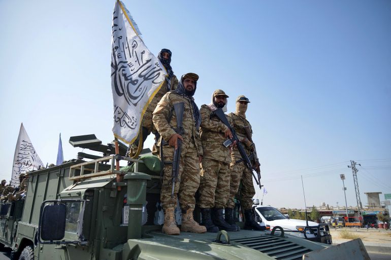 Taliban security personnel of Afghanistan military's 205 Al-Badr Corps carrying Taliban flag, stand atop a military vehicle during a parade to celebrate the third anniversary of Taliban's takeover of the country, in Kandahar on August 14, 2024. - Taliban authorities kicked off celebrations of the third anniversary of their rule over Afghanistan on August 14, at the former US Bagram air base. (Photo by Sanaullah SEIAM / AFP)