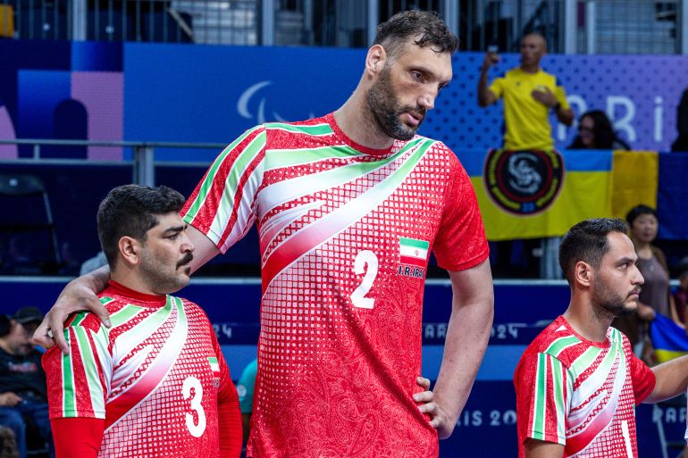 30 August 2024, France, Paris: Paralympics, Paris 2024, sitting volleyball, North Paris Arena, preliminary round Iran - Ukraine, Morteza Mehrzad (M) from Iran, the tallest athlete at the Paralympics at 2.44 meters, stands on the court with his teammates during his country's national anthem. Photo: Jens Büttner/dpa (Photo by Jens Büttner/picture alliance via Getty Images)