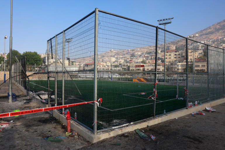 Red tape blocks off a football pitch after a reported strike from Lebanon fell in Majdal Shams village in the Israeli-annexed Golan area on July 28, 2024. - Israel's military said Hezbollah fired the rocket from Lebanon, hitting a football pitch in the Druze town of Majdal Shams and killing the youngsters, who were between 10 and 20 years old. Another 18 youths were wounded in the attack, said the emergency services. (Photo by Menahem Kahana / AFP)