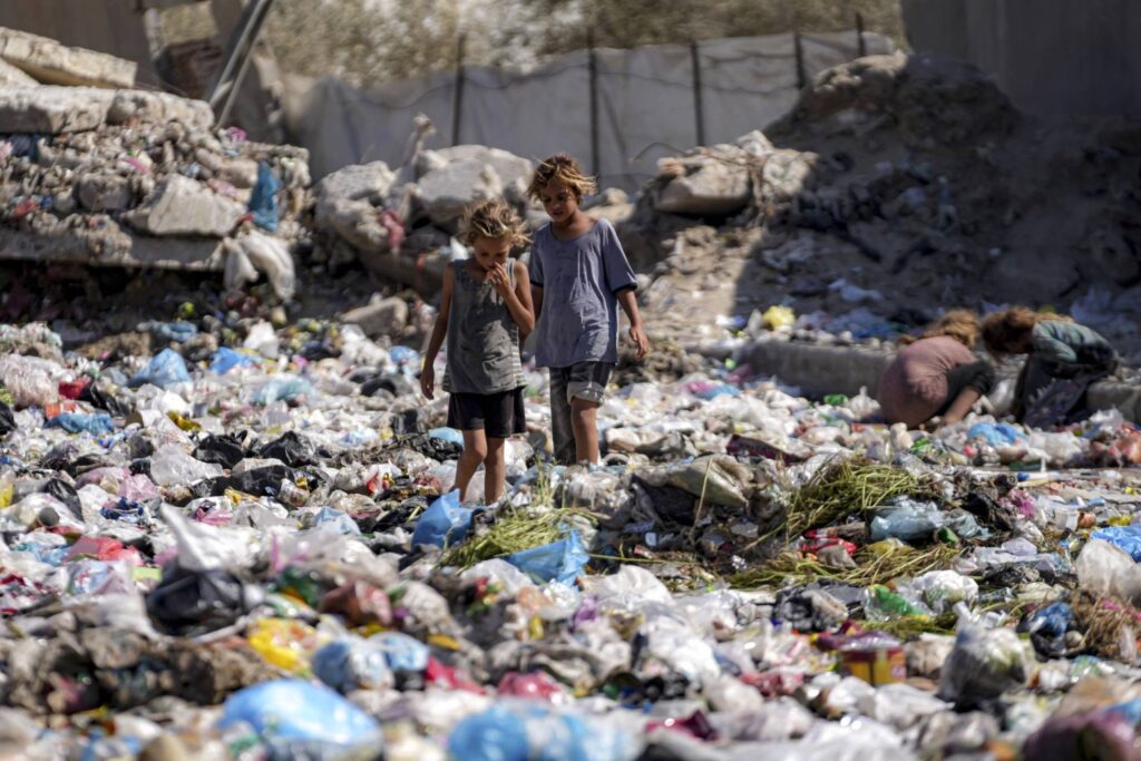 طفلان فلسطينيان نازحان يفرزان القمامة في أحد شوارع دير البلح وسط قطاع غزة في ظل الحرب الدائرة (أ.ب)