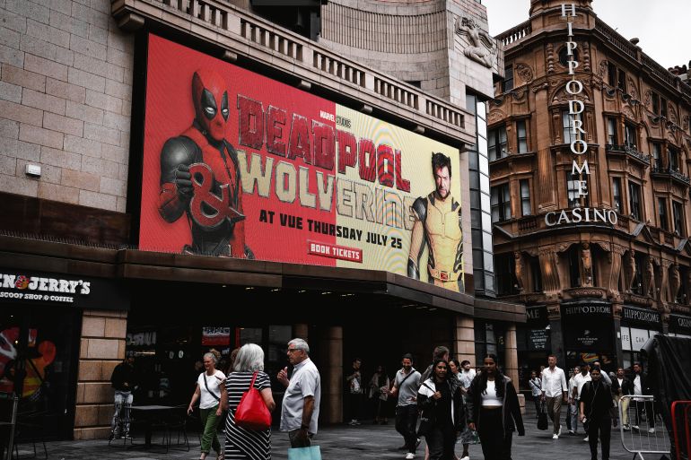 vue west end cinema leicester square, greater london, england – july 22, 2024. vue west end cinema, leicester square: an led readout displaying showtimes, a busy pedestrian area of leicester square, deadpool 3 - deadpool and wolverine, ryan reynolds and hugh jackman; american superhero film featuring marvel comics characters deadpool and wolverine. the hippodrome casino - entertainment hub in leicester square.