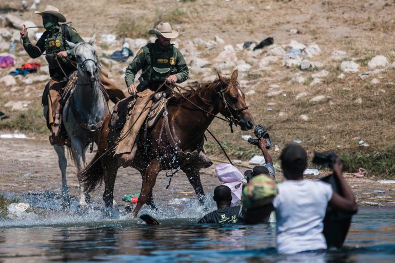 US Customs and Border Protection agents on horseback deployed against Haitian migrants as they cross the Rio Grande from Ciudad Acuña, Mexico, into Del Rio, Texas, September 19, 2021. © 2021 AP Photo/Felix Marquez