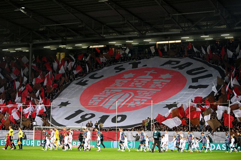 HAMBURG, GERMANY - JANUARY 30: The fans of FC St. Pauli display a Tifo as the players of both teams take to the field prior to kick-off ahead of the DFB cup quarterfinal match between FC St. Pauli and Fortuna Düsseldorf at Millerntor Stadium on January 30, 2024 in Hamburg, Germany. (Photo by Stuart Franklin/Getty Images)